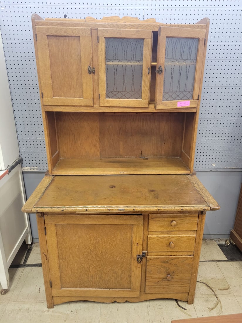 Antique Oak Hoosier-Style Kitchen Cabinet: Antique oak Hoosier-style kitchen cabinet dating to the early 20th century. Features a large work surface with upper cabinet section having three doors, including two with decorative patterned glass p