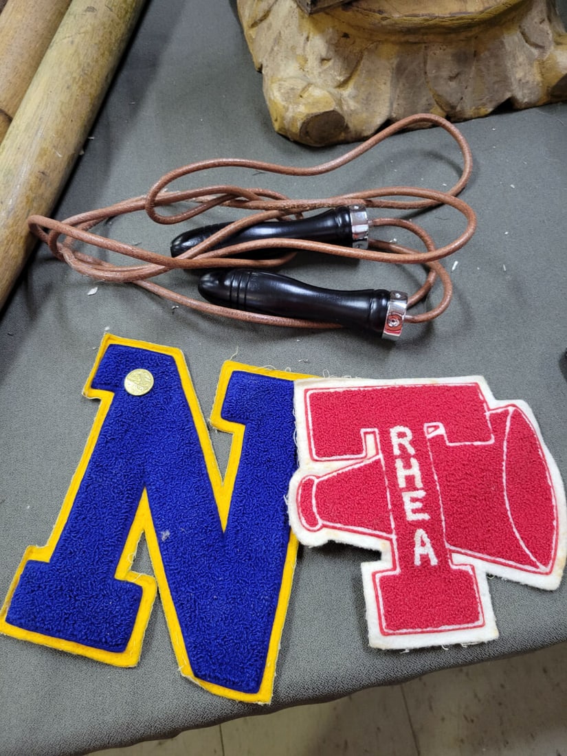 Leather Jump Rope with Wooden Handles and Two Chen: This lot includes a jump rope featuring a leather cord and black-finished wooden handles with metal ferrules. Also included are two chenille varsity-style patches: one blue letter N with a yellow bord