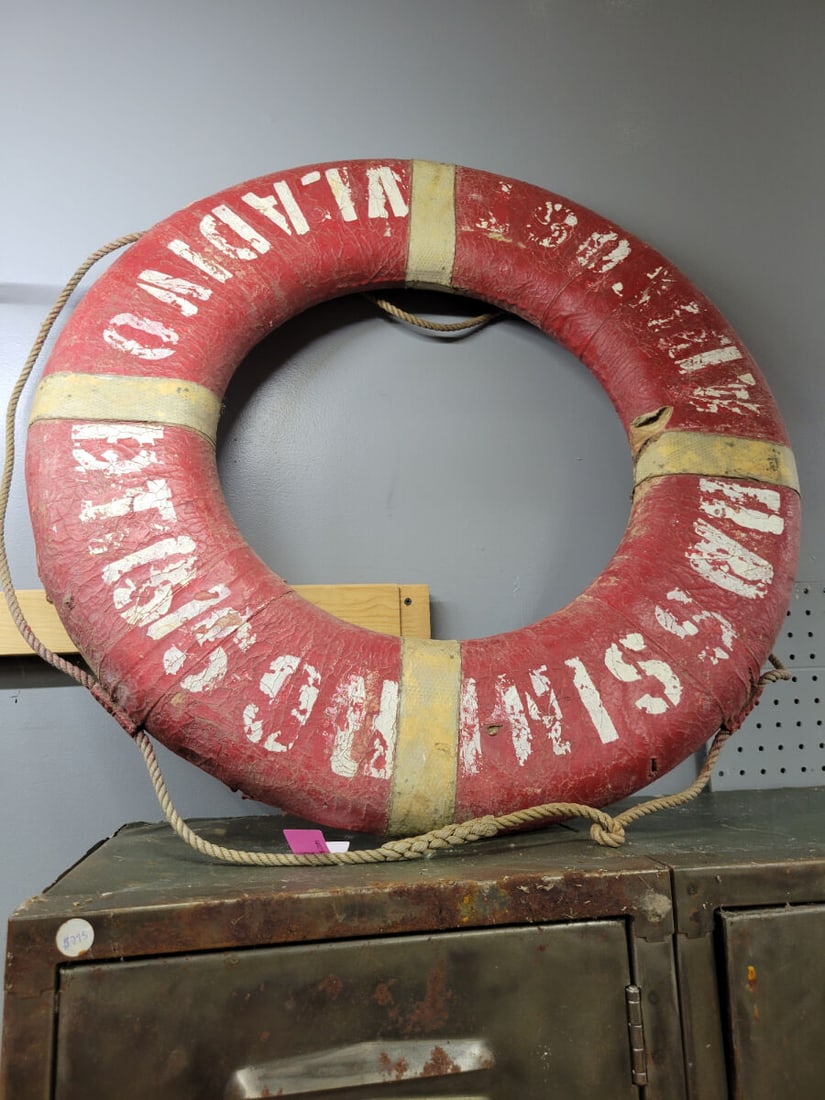 Marine Life Ring Buoy Marked Vladivostok: A circular marine life ring buoy featuring a red exterior with white lettering reading Vladivostok. The buoy includes integrated rope detailing and light-colored accent bands.