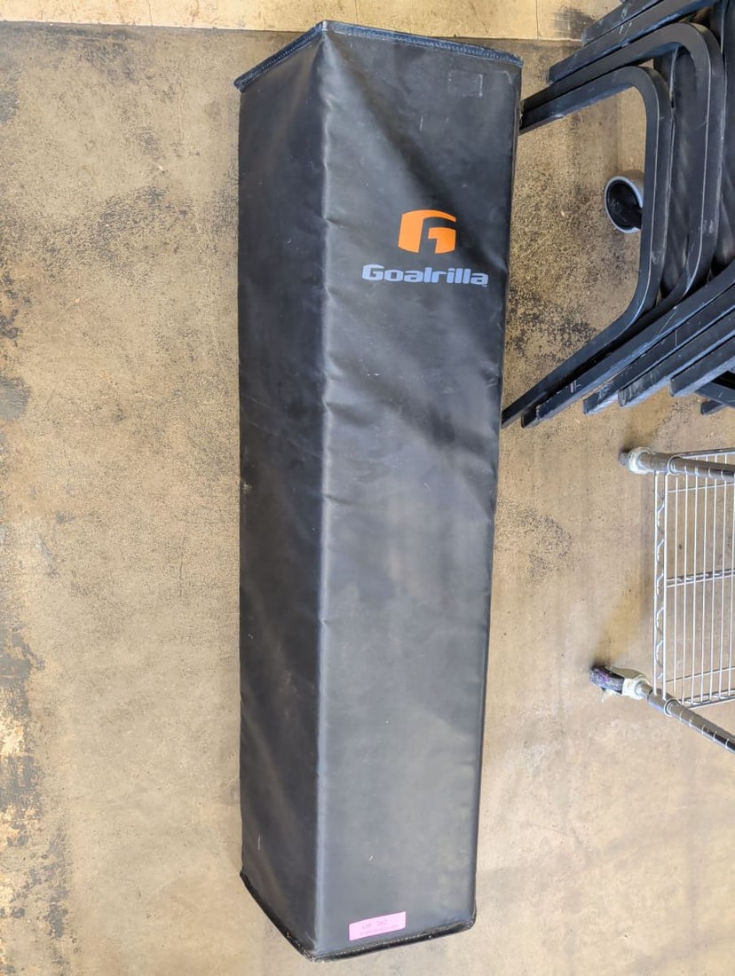 Goalrilla Basketball Pole Safety Pad: A black, rectangular protective pole pad featuring the Goalrilla logo. The pad is constructed with a durable exterior material and includes integrated straps on the reverse side for attachment to a ba