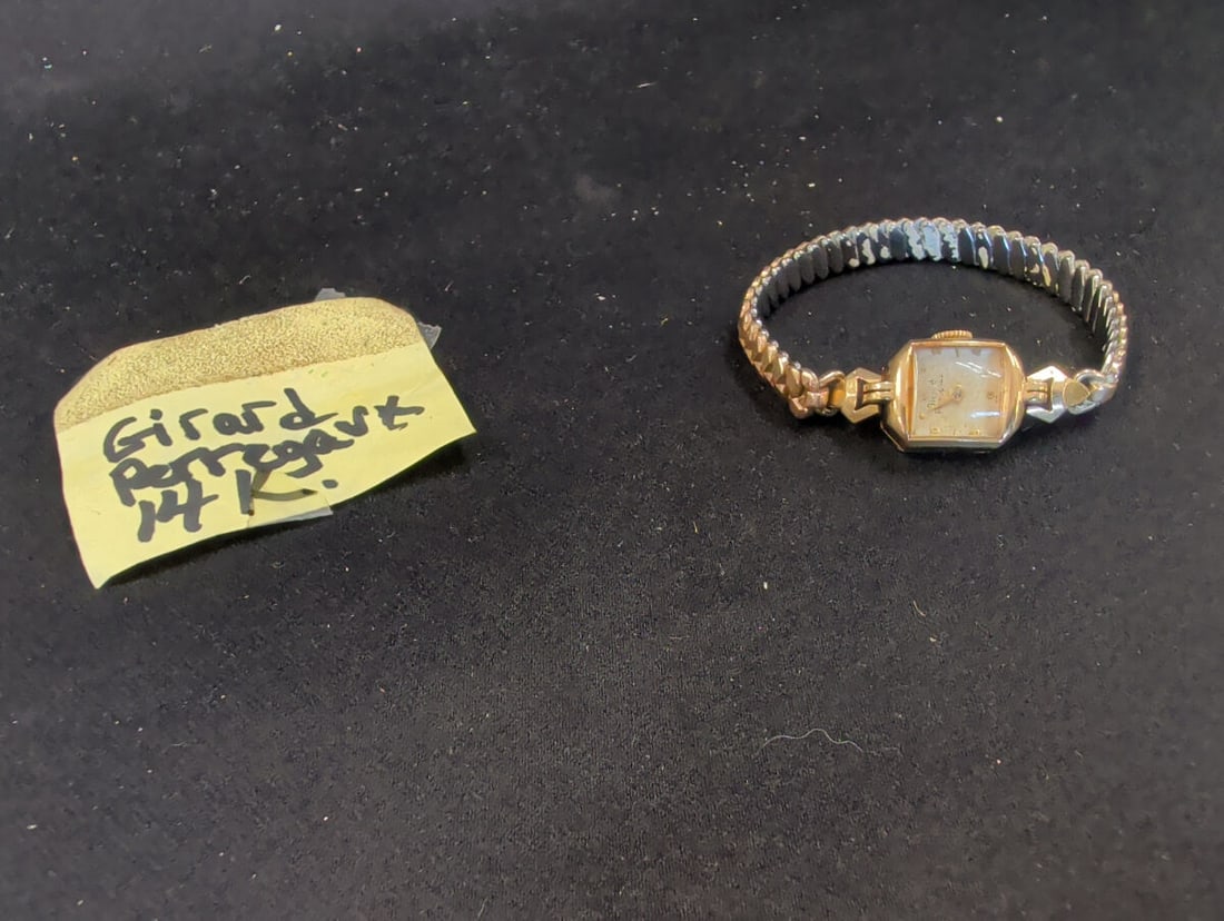 Girard-Perregaux 14K Gold Ladies Wristwatch: A Girard-Perregaux ladies wristwatch featuring a 14K gold case, as indicated by the hallmark on the side of the housing. The watch is paired with an expandable metal bracelet. The dial displays the Gi