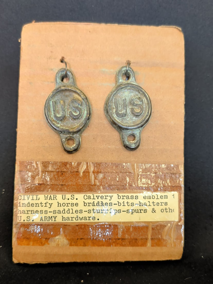 Pair of U.S. Military Brass Horse Tack Emblems: A pair of circular brass emblems featuring the letters U.S. in relief. Each piece includes two mounting holes for attachment to leather horse tack, such as bridles, halters, or harnesses. The items