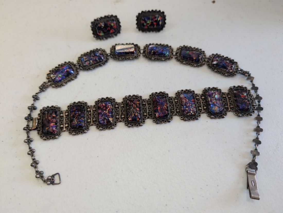 Mexican Silver and Iridescent Glass Jewelry Set: A jewelry set consisting of a link bracelet and a pair of clip-on earrings. The pieces feature rectangular, iridescent glass cabochons set in silver frames with decorative wirework borders. The bracel