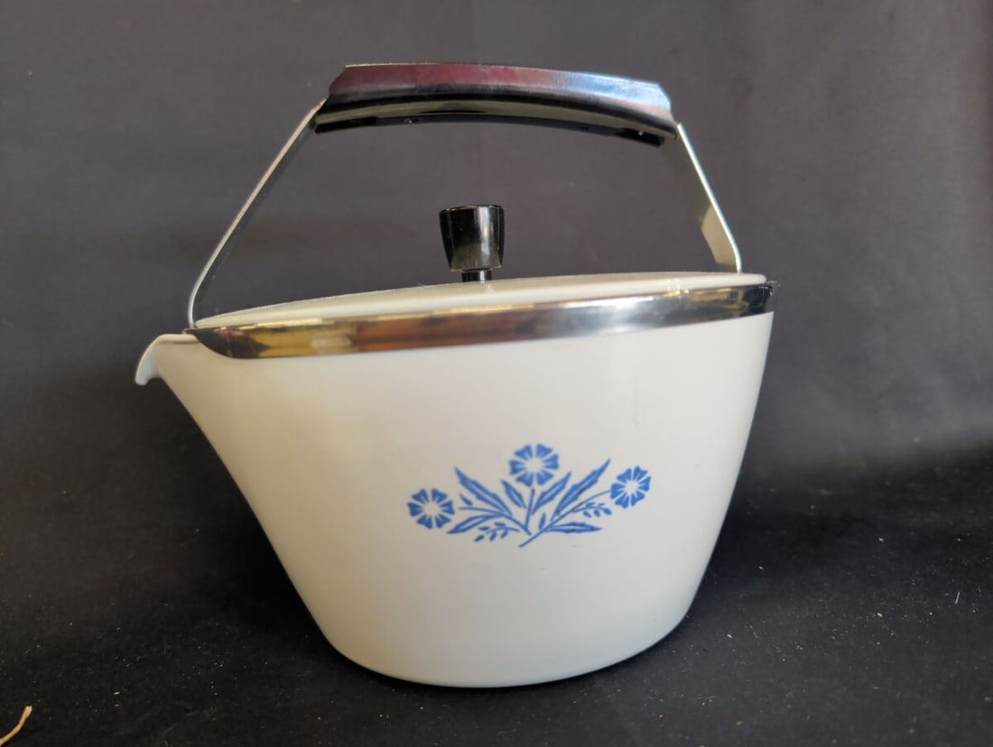 Corning Ware P-57-B 2 Quart Teakettle Blue Cornflo: A 2-quart Corning Ware teakettle featuring the Blue Cornflower pattern. The unit includes a metal handle, a lid with a black knob, and a metal rim. The base is marked P-57-B and indicates it was made 