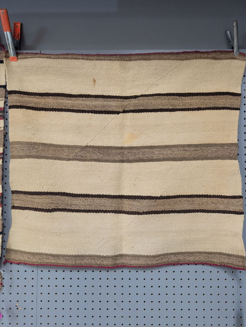 Woven Wool Textile with Striped Pattern 28x29: A hand-woven wool textile featuring a repeating horizontal striped pattern in natural cream, tan, and dark brown tones. The piece is finished with a red edge binding along the top and bottom borders. 