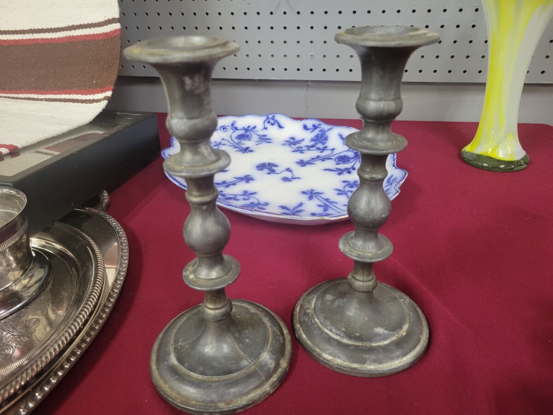 Pair of Metal Candlestick Holders: A set of two metal candlestick holders featuring a turned stem design and circular bases. The undersides of the bases are lined with felt, with one base showing partial detachment of the felt lining.
