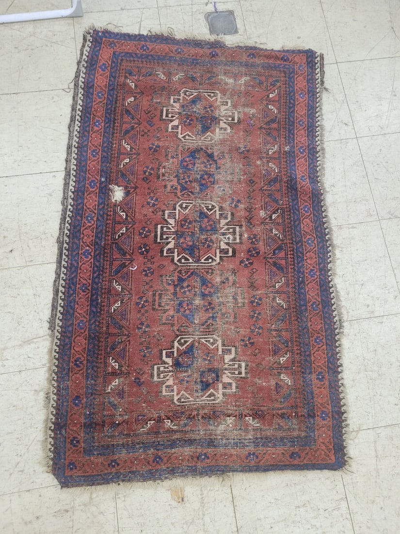 Hand-Knotted Wool Area Rug with Geometric Medallio: A hand-knotted wool area rug featuring a repeating geometric medallion pattern in shades of red, blue, and cream. The rug includes a multi-layered border with triangular and floral motifs. The piece e