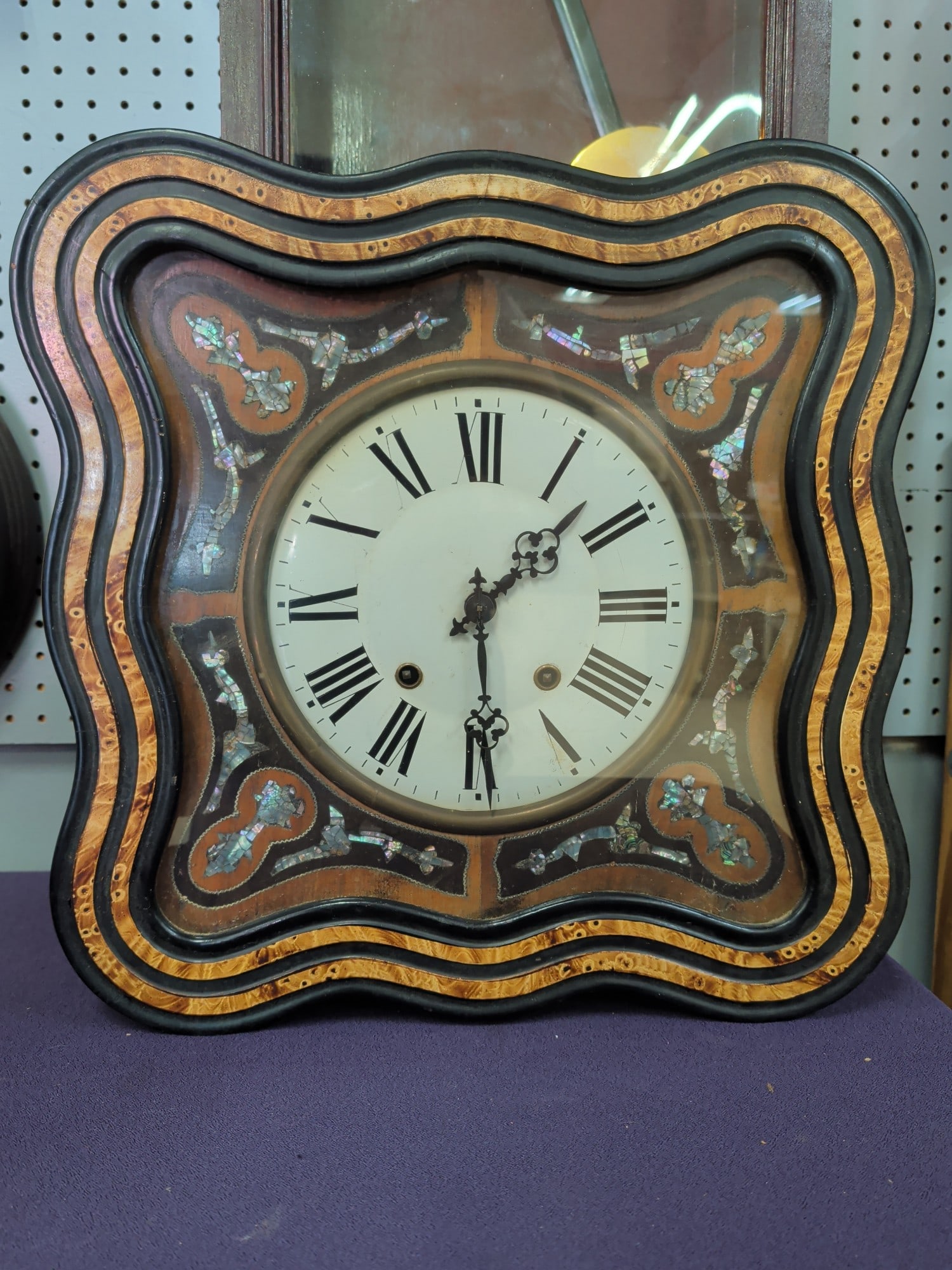 Victorian Mother of Pear Inlayed Cartel Wall Clock: Elegant Victorian Cartel-style wall clock featuring a shaped ebonized and burl veneer case richly decorated with iridescent mother-of-pearl floral and foliate inlay. The clock is fitted with a porcela