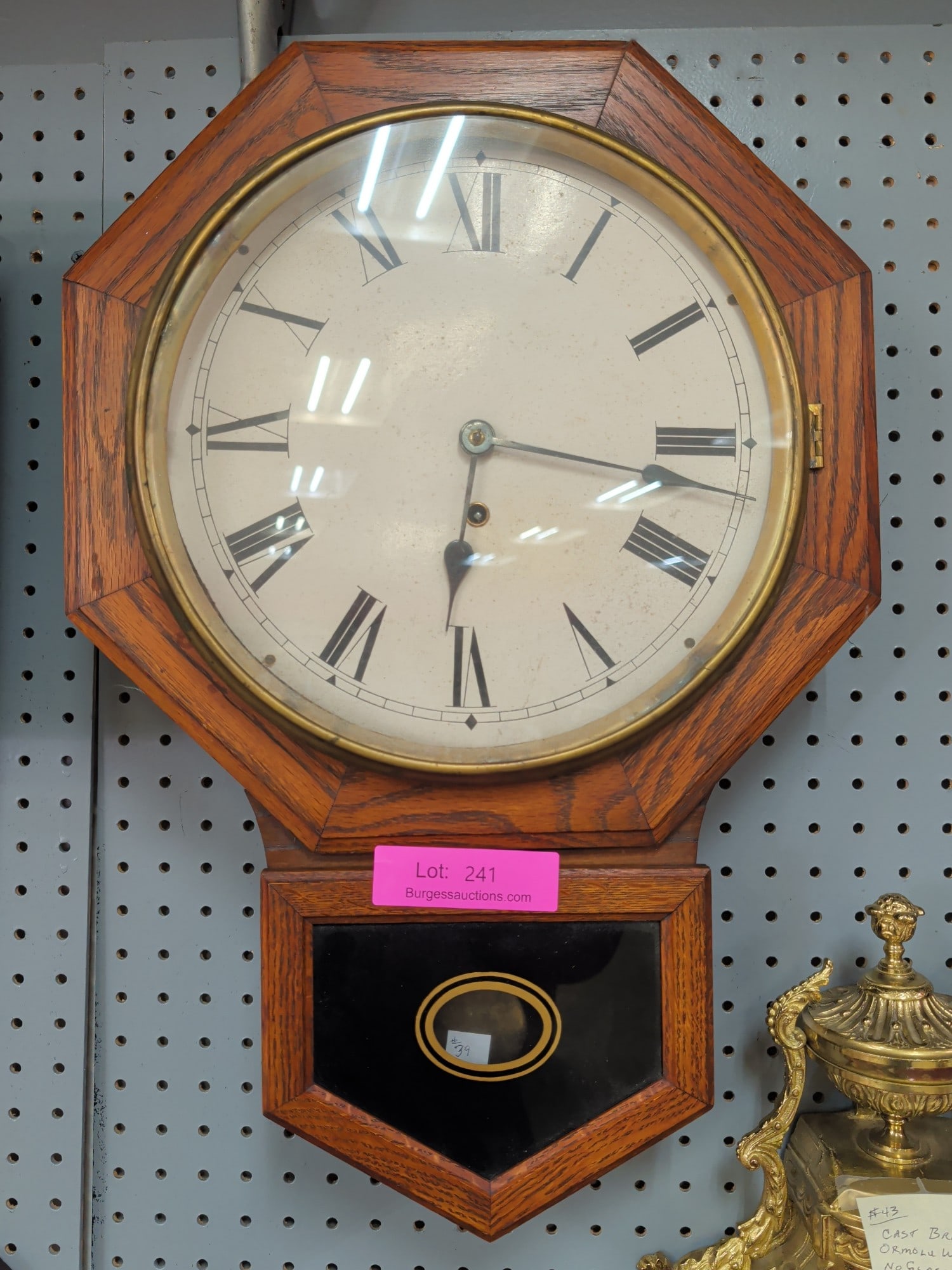 Waterbury Short Drop Regulator Wall Clock, Oak Cas: Antique Waterbury Short Drop Regulator Wall Clock featuring an attractive oak case with octagonal dial surround, lower glazed pendulum compartment with black tablet and gilt oval decoration, and a lar