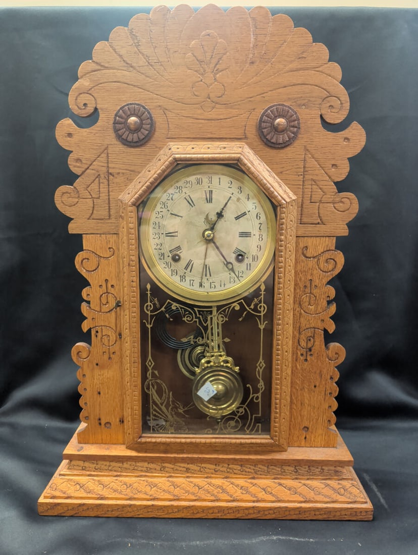 Eastlake Oak Gingerbread Shelf Clock with Calendar: Late 19th-century Eastlake style gingerbread shelf clock housed in a richly carved oak case with fan crest, geometric carvings, and decorative rosette appliques. The clock features a paper Roman numer