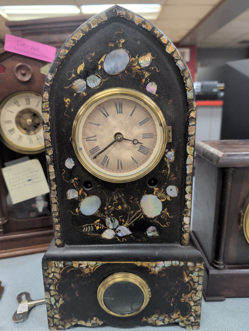 Victorian Cathedral Mantel Clock with Mother-of-Pe: Victorian cathedral-style mantel clock featuring a black lacquered case lavishly decorated with mother-of-pearl inlay and hand-applied gilt floral and vine accents. The arched case houses a paper