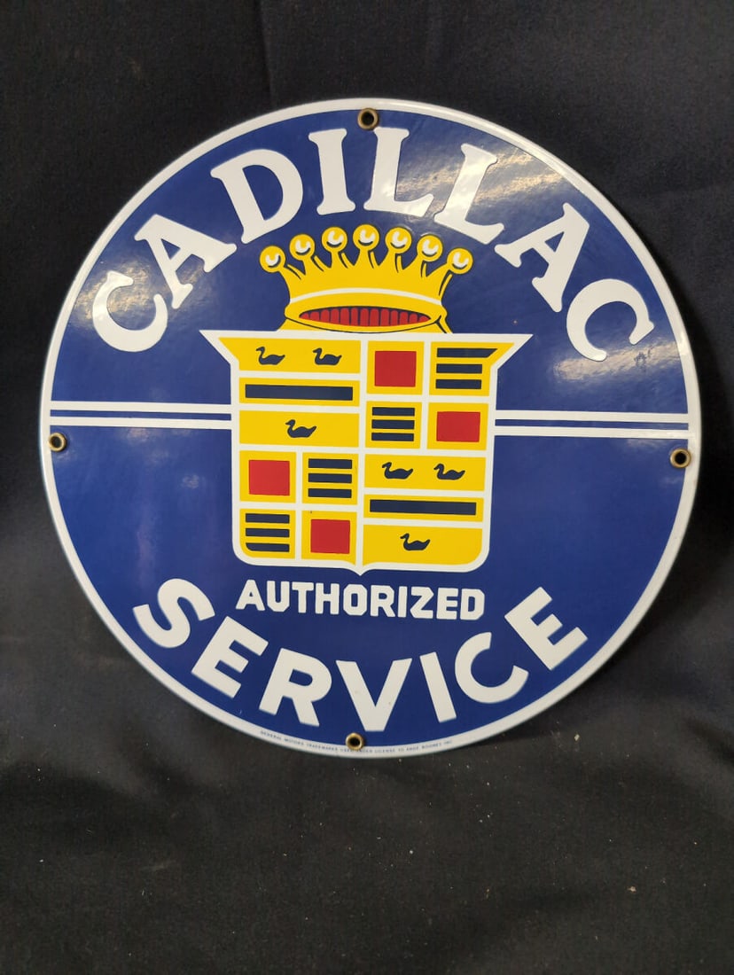 Cadillac Authorized Service Round Metal Sign: A round metal sign featuring the Cadillac Authorized Service logo with classic crest and crown graphics in blue, yellow, red, and white. The sign includes pre-drilled mounting holes with brass