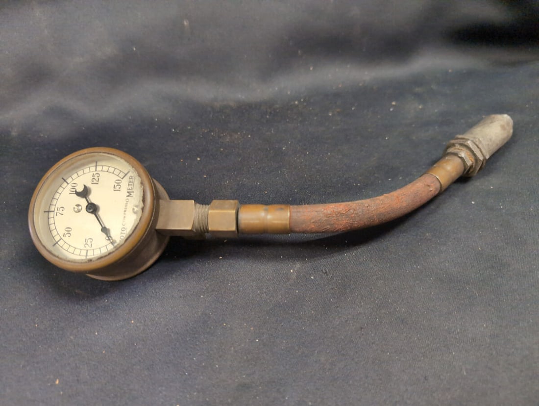Moto Compresso Meter Pressure Gauge with Flexible Hose: Moto Compresso Meter pressure gauge featuring a brass housing, a white face marked up to 150 PSI, and a patent date of March 18, 1919. The instrument includes a flexible rubber hose with a fabric