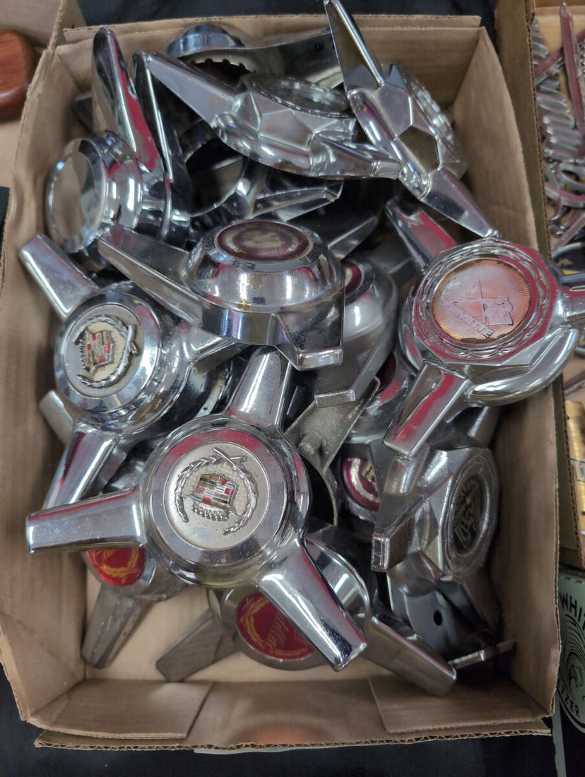 Assorted Lot of Chrome Spinner Hubcaps and Center Caps including Cadillac and Star Wire: A collection of chrome spinner hubcaps and wheel center caps featuring various brand emblems such as Cadillac, Star Wire, and Corvette. These automotive accessories showcase a bright finish and three-
