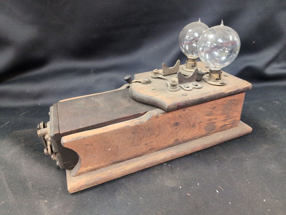 No. 28 Combination Tester, 110 Volts 60 Cycles, Wooden Base with Two Bulbs: A No. 28 Combination Tester housed in a wooden base, designed for alternating current only at 110 volts and 60 cycles. The unit features dual light bulbs mounted on top, exposed brass and metal