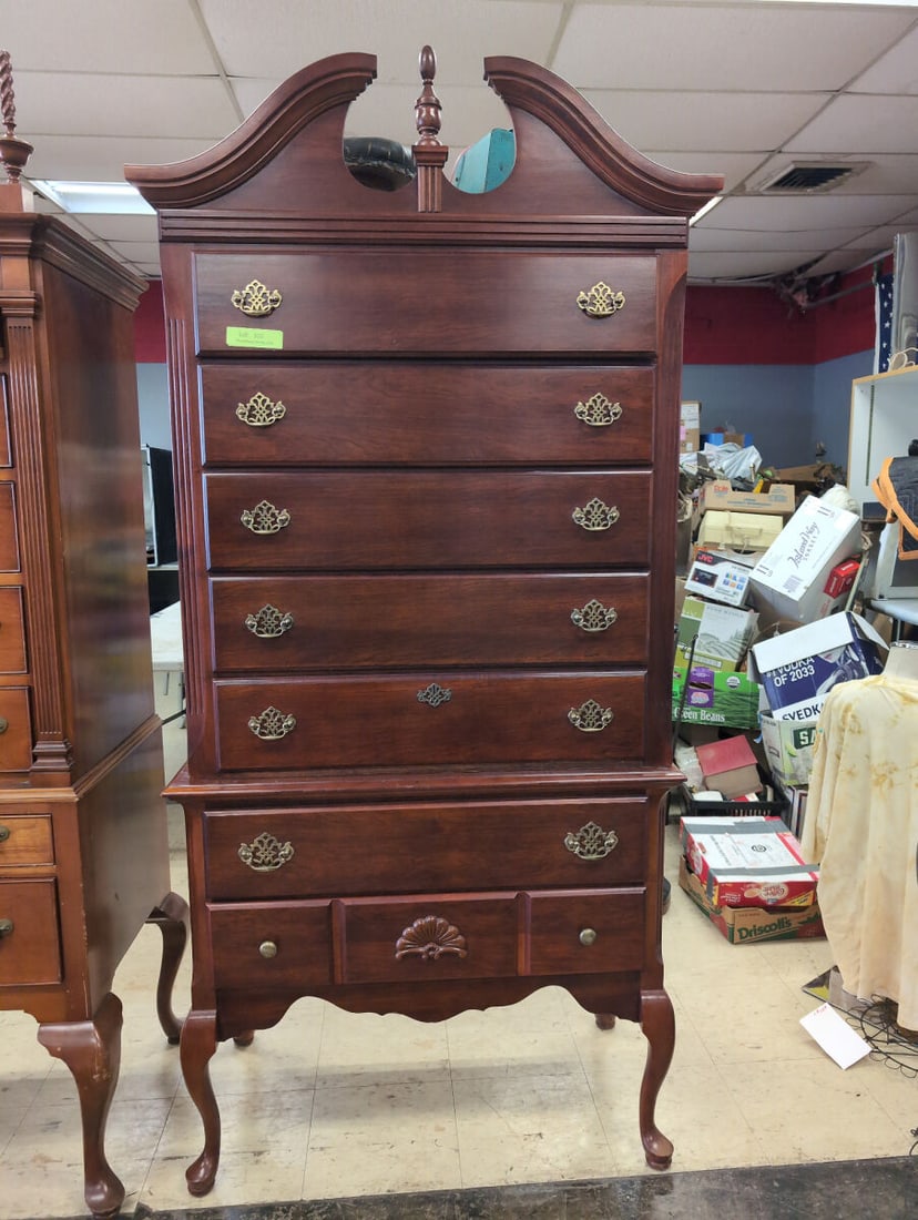 Tall Dark Wood Highboy Dresser with Pediment Top and Brass Hardware: Tall dark wood highboy dresser featuring multiple drawers, ornate brass-tone hardware pulls, a scalloped skirt with cabriole legs, and a decorative swan neck pediment top with a center finial. Measure