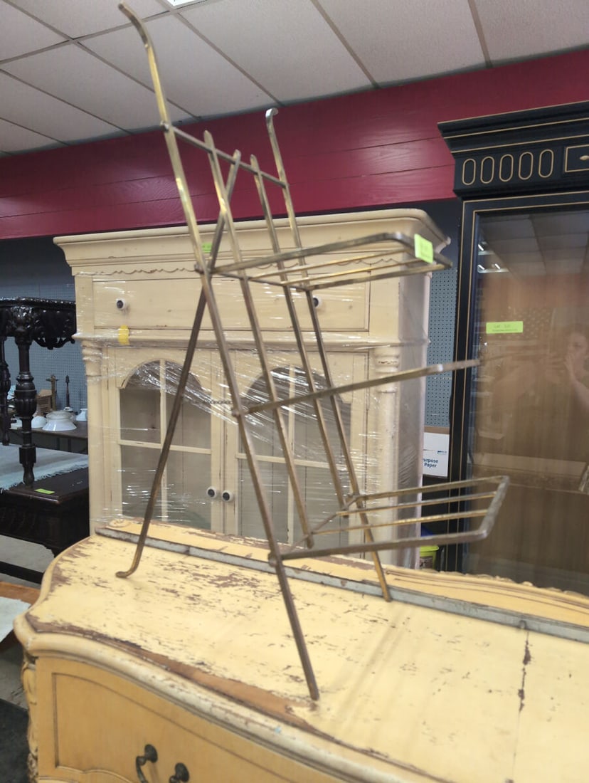 Brass Folding Three-Tier Display Stand: Brass folding three-tier display stand featuring an open wire rack design with multiple shelves supported by an X-frame structure. The unit collapses for storage and transport. Measures overall