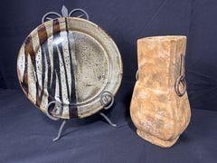 Vintage Vase and Platter: Vintage Hand Made Clay Vase with Iron Accents. Has markings from artist on the bottom. Also glazed Ceramic Stone Plate 12 inches round. Has markings on the back. Collectible Items. Stand not included.