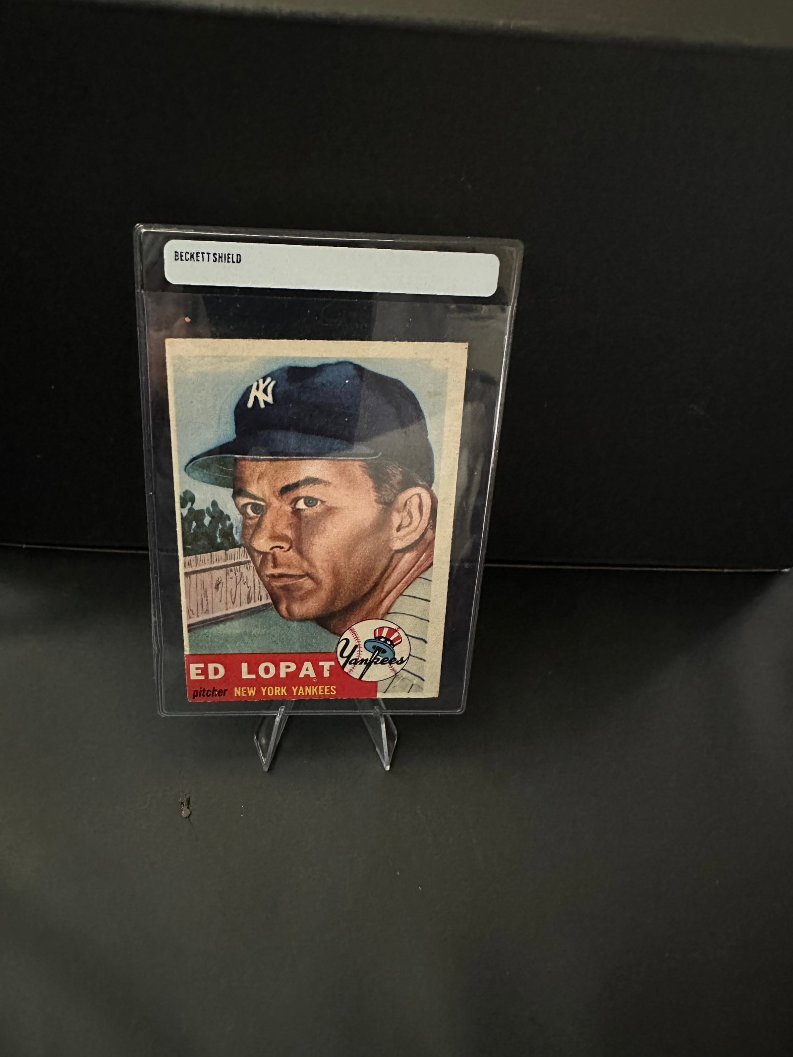 1952 Ed Lopat New York Yankees Sports Card: This is a 1952 Ed Lopat baseball card featuring the legendary New York Yankees pitcher. The card showcases Lopat in his Yankees cap, reflecting the classic design of the 1950s sports trading cards. It