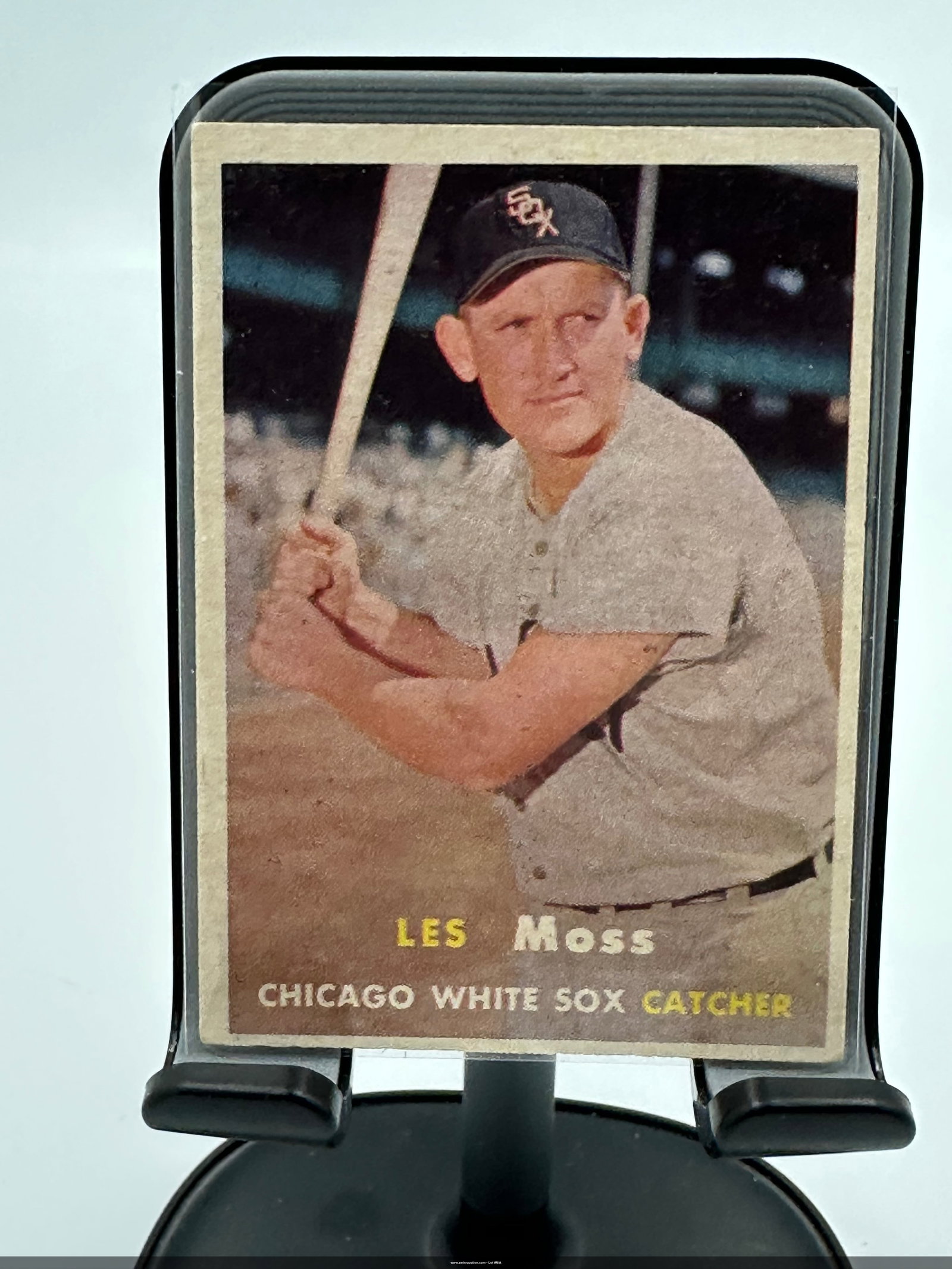 1957 Topps Les Moss Baseball Card: Les Moss, a catcher for the Chicago White Sox. The card showcases Moss in a batting stance against a backdrop of a baseball field, with the team name and player name prominently displayed. It is part 
