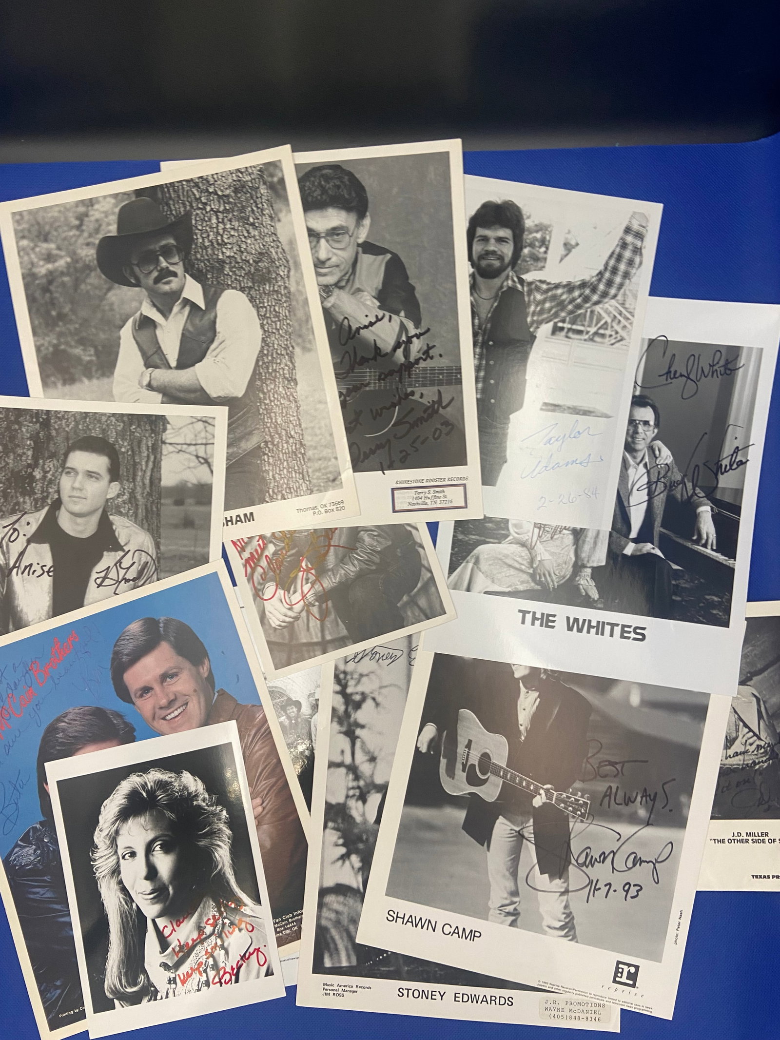 Collection of Autographed Country Music Photos: collection of autographed black-and-white photos featuring various country music artists. Notable names include Shawn Camp, who is depicted holding a guitar, along with other artists who have signed