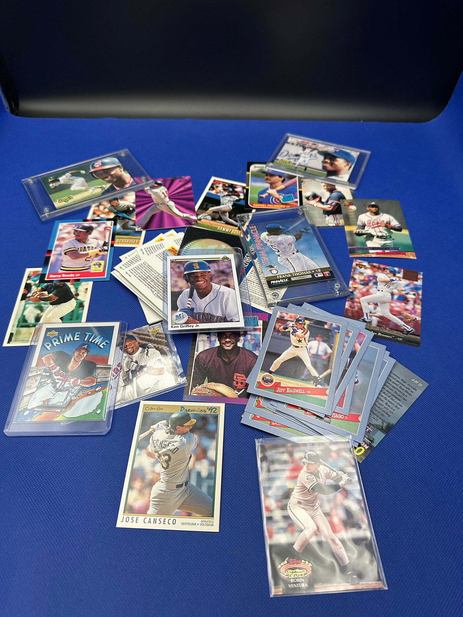 Collection of Baseball Trading Cards: a diverse collection of sports trading cards featuring various players, spanning multiple years and teams. Among the cards, notable figures such as José Canseco