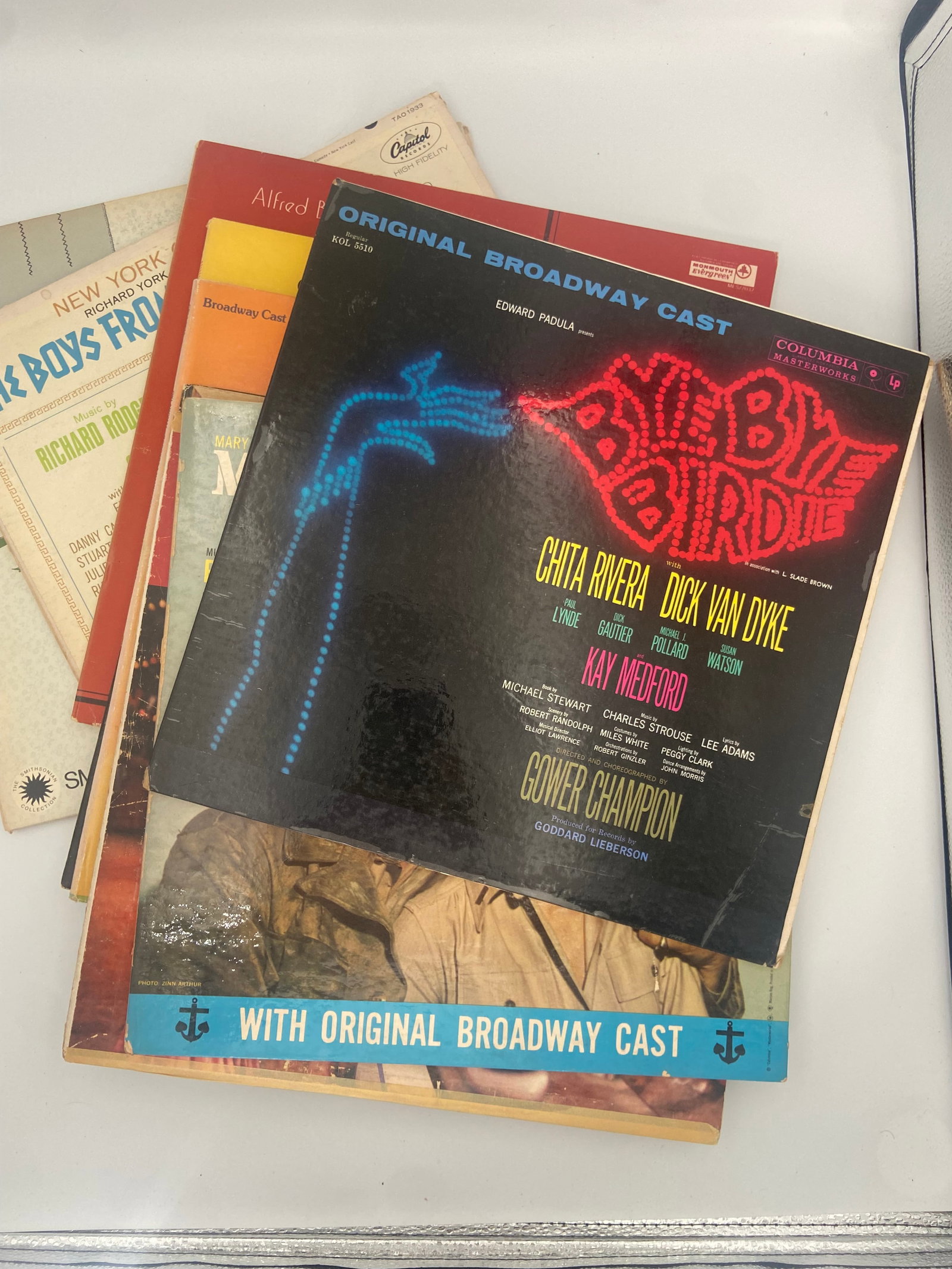 Vintage Vinyl Record Albums Featuring Original Broadway Cast Recordings: A collection of vintage vinyl record albums featuring original broadway cast recordings. The stack includes titles such as bye bye birdie and various other musical theater soundtrack records. These