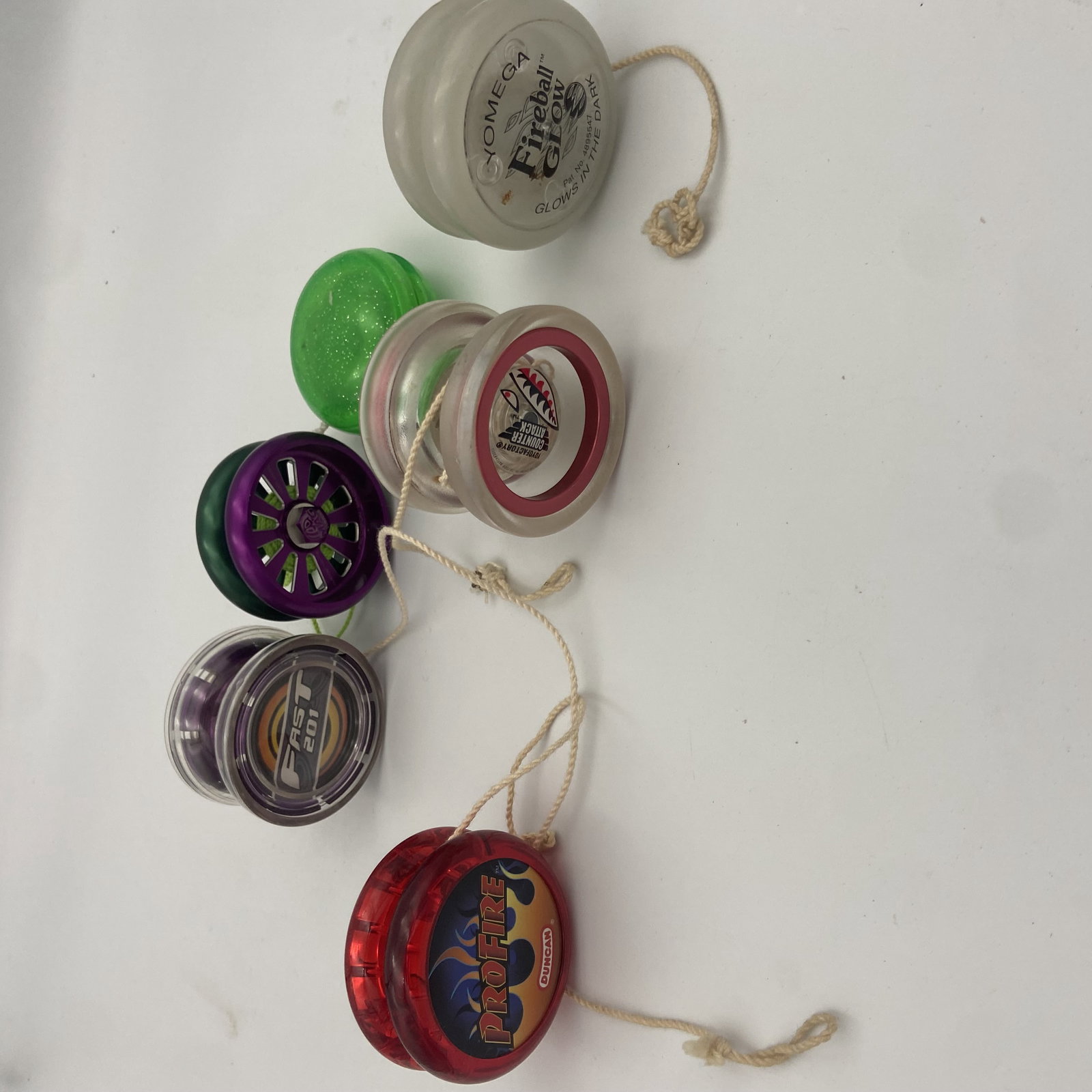 Vintage Duncan and YoYoFactory Yo-Yo Collection: ot features a collection of vintage and modern yo-yos including a glow-in-the-dark Duncan Omega Fireball, a red Duncan ProFire, a purple YoYoFactory Fast 201, and other assorted models. These yo-yos
