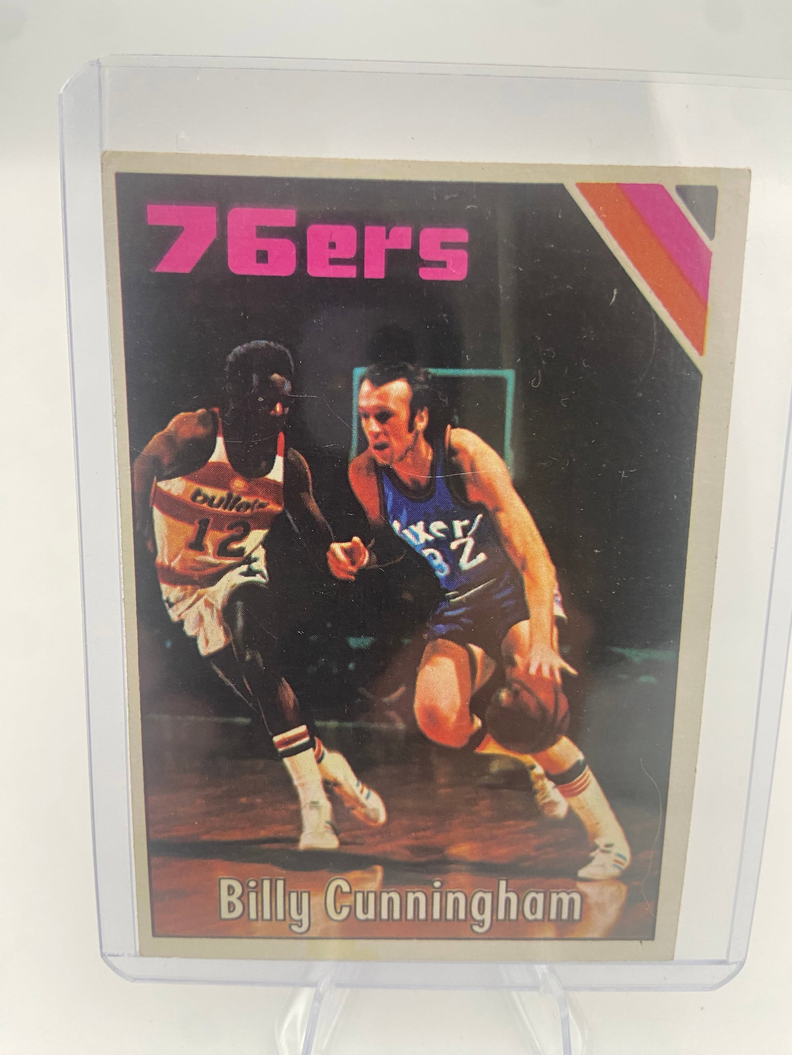 1972-73 Topps Billy Cunningham Basketball Card: This is a 1972-73 Topps basketball trading card featuring Billy Cunningham of the Philadelphia 76ers. The card features a vibrant design typical of the early 1970s and is protected in a clear plastic