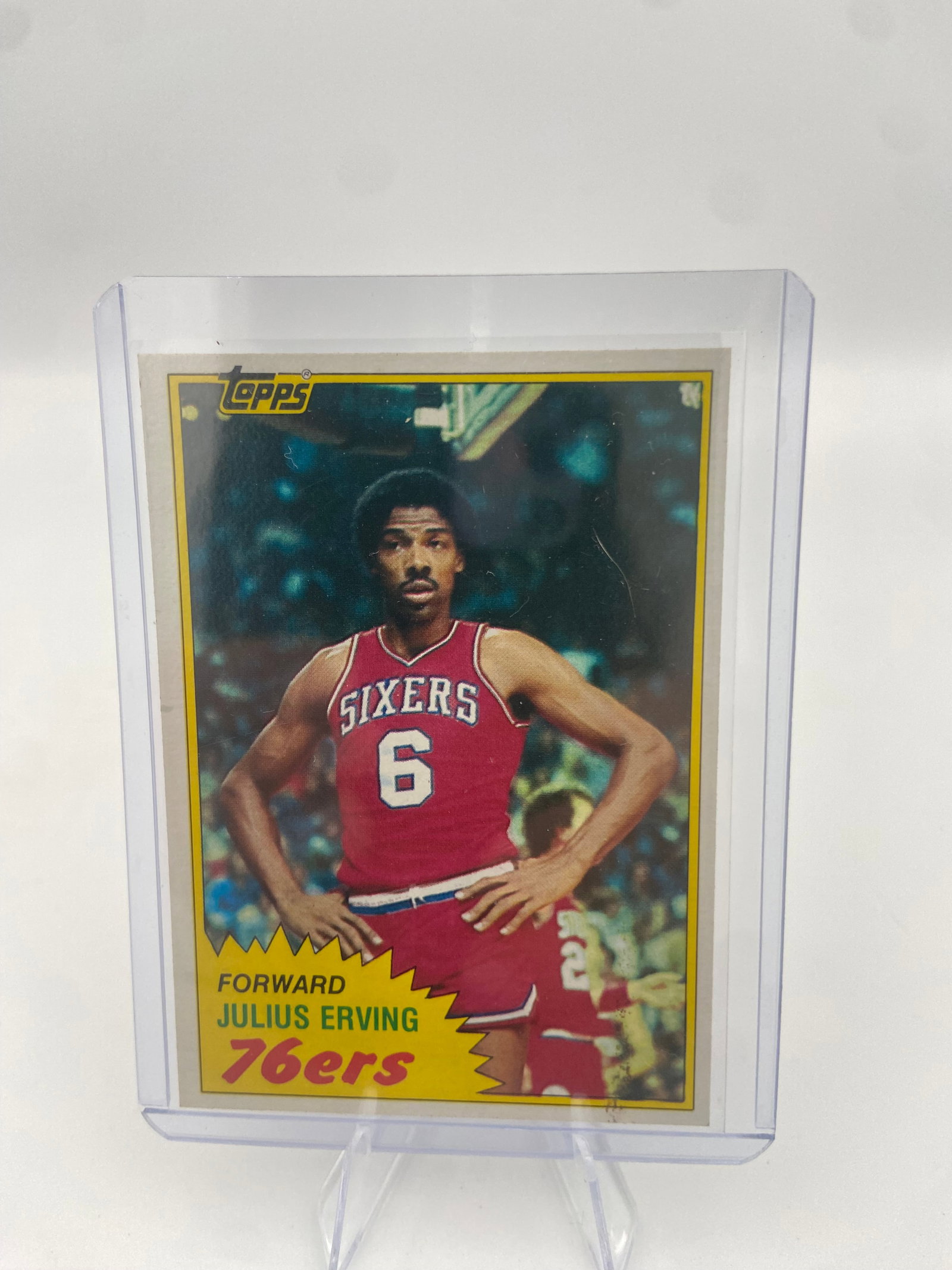 1977 Topps Julius Erving Basketball Card: This is a 1977 Topps basketball trading card featuring legendary NBA player Julius Erving. The card depicts Erving in his Philadelphia 76ers uniform and is encased in a protective plastic top loader.