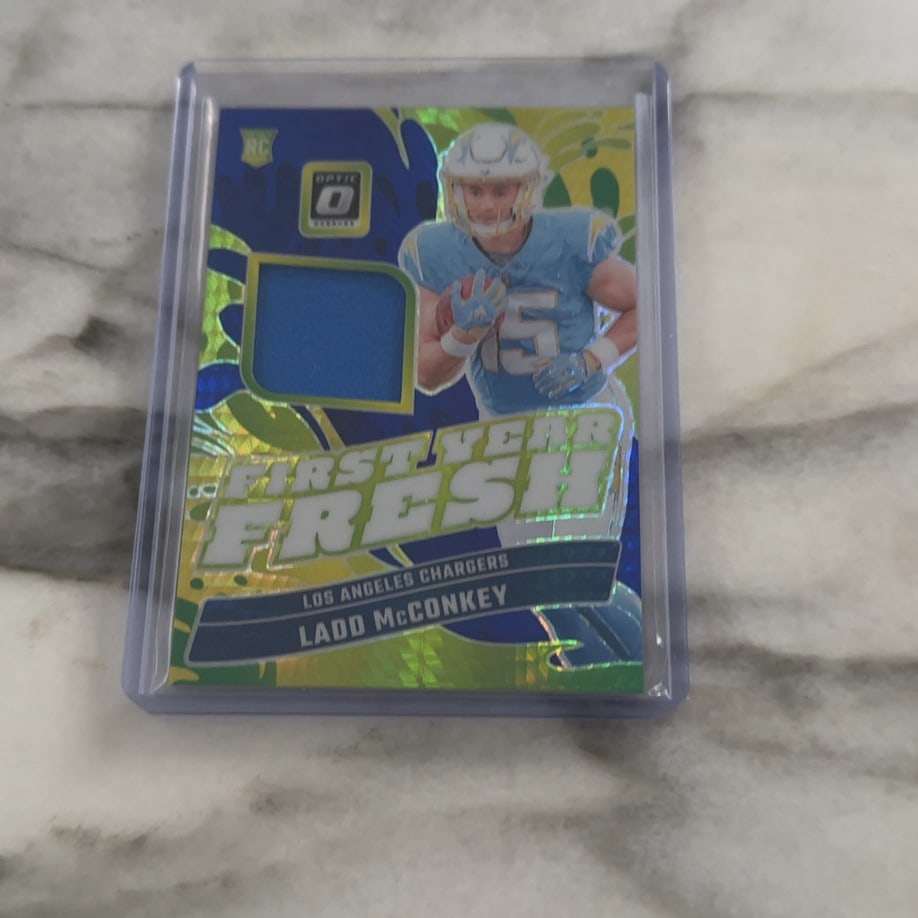 2024 Donruss Optic First Year Fresh Ladd McConkey Blue Hyper: This is a 2024 Donruss Optic 'First Year Fresh' rookie card featuring Los Angeles Chargers wide receiver Ladd McConkey. The card includes a blue jersey relic swatch and features a vibrant,