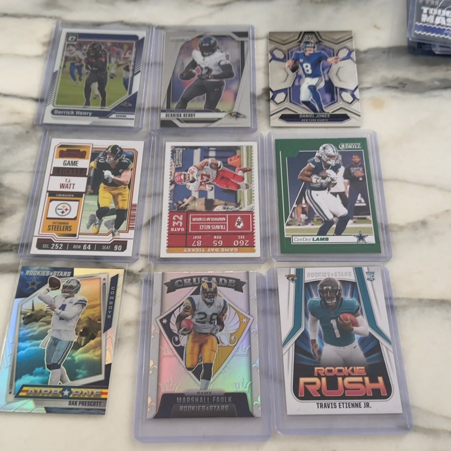 Assorted NFL Football Trading Cards Lot: This is a collection of various NFL football trading cards, featuring players such as Derrick Henry, T.J. Watt, and Travis Etienne Jr. The cards include different series and styles like Rookies &