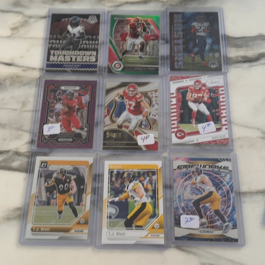 NFL Football Trading Card Collection: This is a collection of nine NFL football trading cards featuring players Derrick Henry, Travis Kelce, and T.J. Watt. The cards are enclosed in individual plastic protective cases and include various