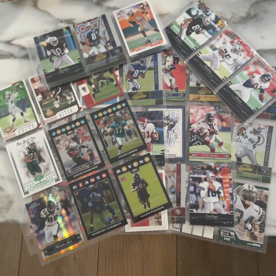 Assorted NFL Football Trading Cards Collection: This is a collection of various NFL football trading cards displayed in plastic storage pages. The cards feature multiple players from different teams and seasons, including Jerry Rice, Michael
