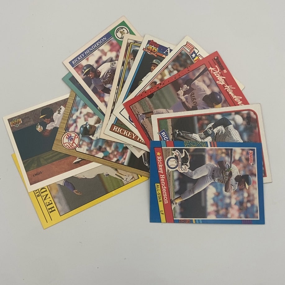 Rickey Henderson Baseball Card Lot: A collection of Rickey Henderson baseball cards from various manufacturers. Visible cards include a 1991 Donruss All-Star #53, a 1990 Donruss #304, a 1991 Topps card, and a 1987 Topps card. The lot
