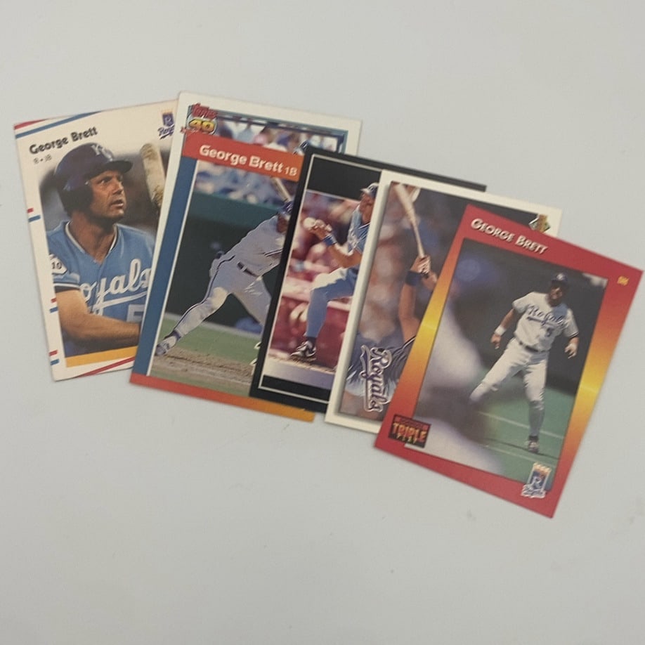 George Brett Baseball Card Lot: his lot features multiple baseball cards depicting Kansas City Royals player George Brett. The cards showcase various action shots and portraits of the player in his uniformRaw - ungraded - condition