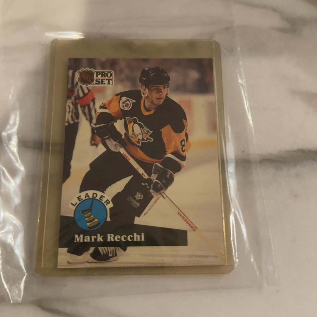 1991 Pro Set Mark Recchi Hockey Card: This is a 1991 Pro Set hockey trading card featuring Pittsburgh Penguins player Mark Recchi. The card is labeled as a leader card and comes protected in a plastic sleeve. It is a classic example of