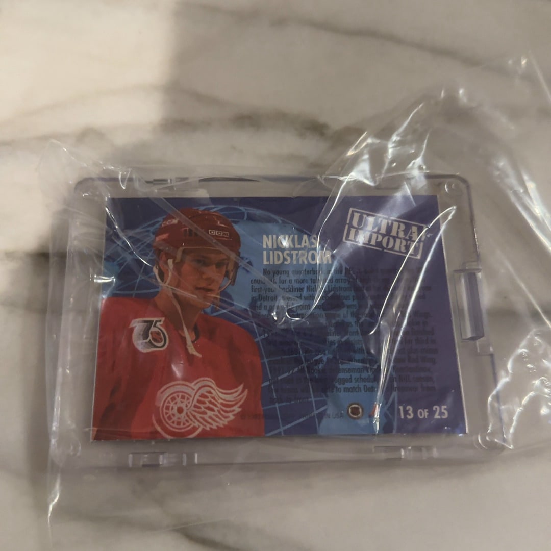 1992-93 Ultra Import Nicklas Lidstrom Hockey Card: This is a 1992-93 Fleer Ultra Import hockey card featuring Detroit Red Wings defenseman Nicklas Lidstrom. The card is encased in a plastic holder and remains sealed in a protective clear sleeve.