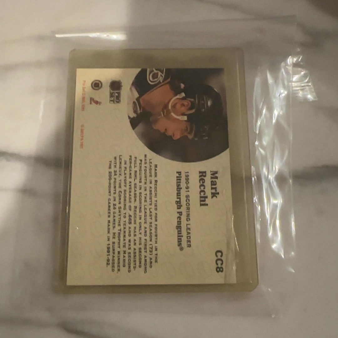 1991-92 Pro Set Mark Recchi CC8 Hockey Card: This is a 1991-92 Pro Set hockey trading card featuring Pittsburgh Penguins player Mark Recchi. The card is labeled CC8 and highlights his 1990-91 scoring leader status. It comes protected in a rigid