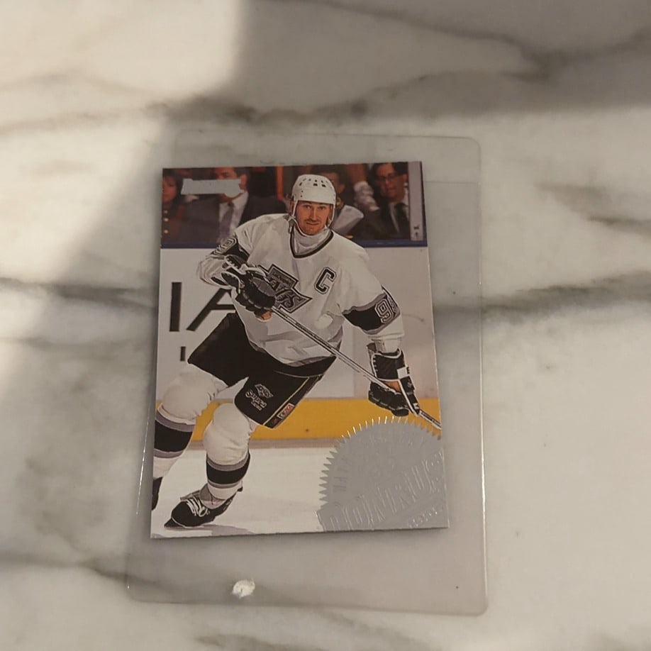 Wayne Gretzky 1995-96 Donruss Hockey Card: This is a 1995-96 Donruss hockey card featuring Wayne Gretzky playing for the Los Angeles Kings. The card showcases Gretzky in his iconic uniform with a distinct foil stamp logo in the bottom corner. 