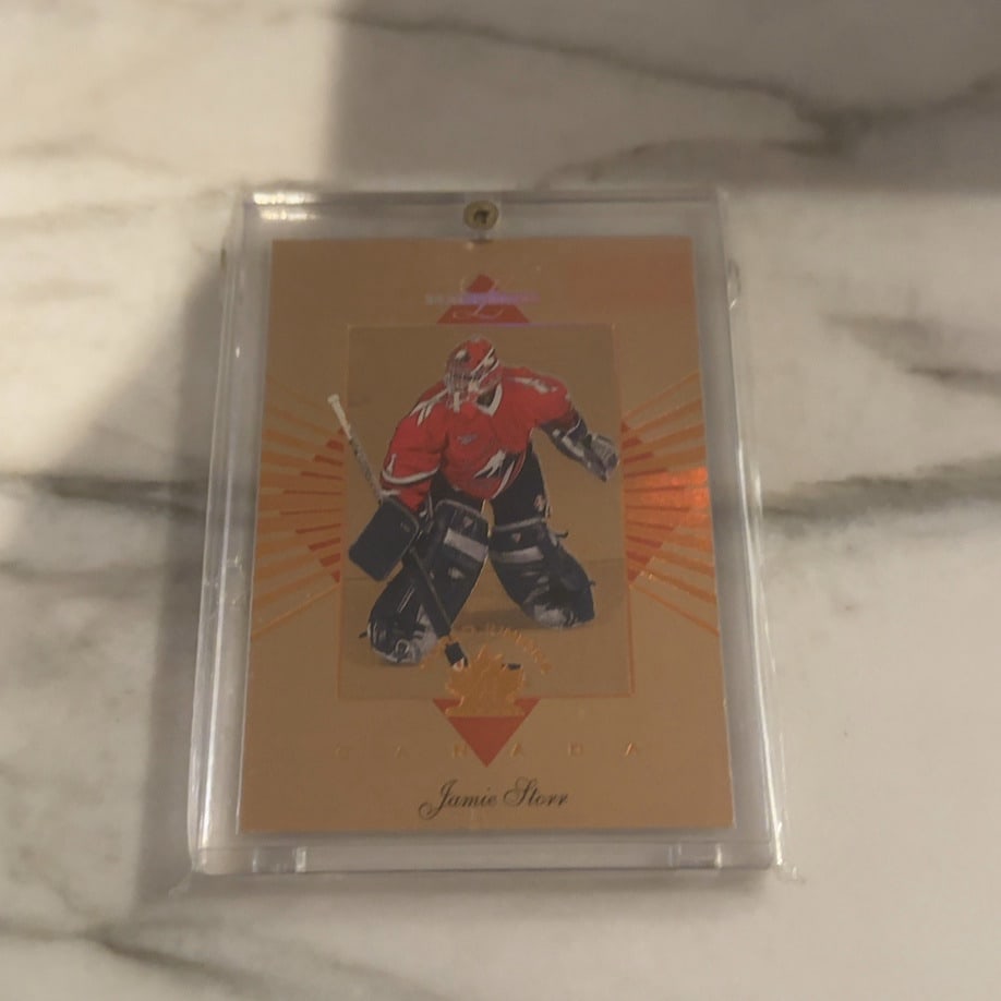 Jamie Storr 1996-97 Pinnacle Certified Hockey Card: This is a 1996-97 Pinnacle Certified trading card featuring hockey goaltender Jamie Storr. The card is encased in a protective magnetic holder and showcases a gold-themed design with the player repres