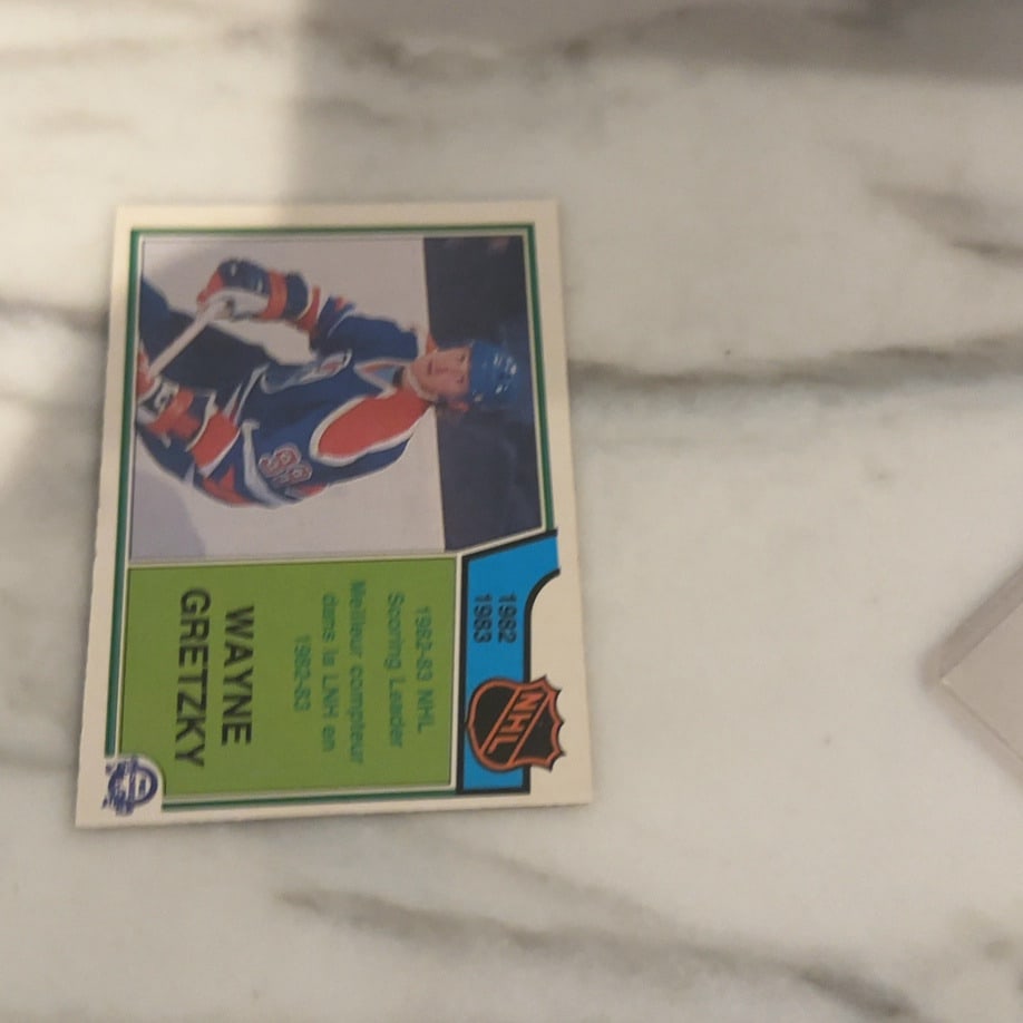 1983-84 O-Pee-Chee Wayne Gretzky Scoring Leader Card: This is a 1983-84 O-Pee-Chee NHL hockey card featuring Wayne Gretzky as the 1982-83 NHL Scoring Leader. The card features both English and French text, which is characteristic of O-Pee-Chee issues. It