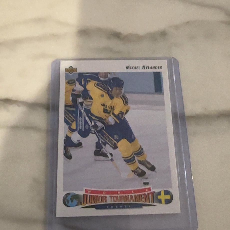 1992 Upper Deck World Junior Tournament Mikael Nylander: This is a 1992 Upper Deck hockey card featuring Mikael Nylander representing Sweden in the World Junior Tournament. The card is encased in a protective plastic top loader. It highlights Nylander in