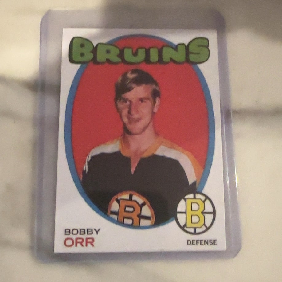 1971 O-Pee-Chee Bobby Orr Hockey Card: This is a 1971 O-Pee-Chee hockey card featuring legendary Boston Bruins defenseman Bobby Orr. The card displays a classic portrait within an oval frame with the team name and player information clearl