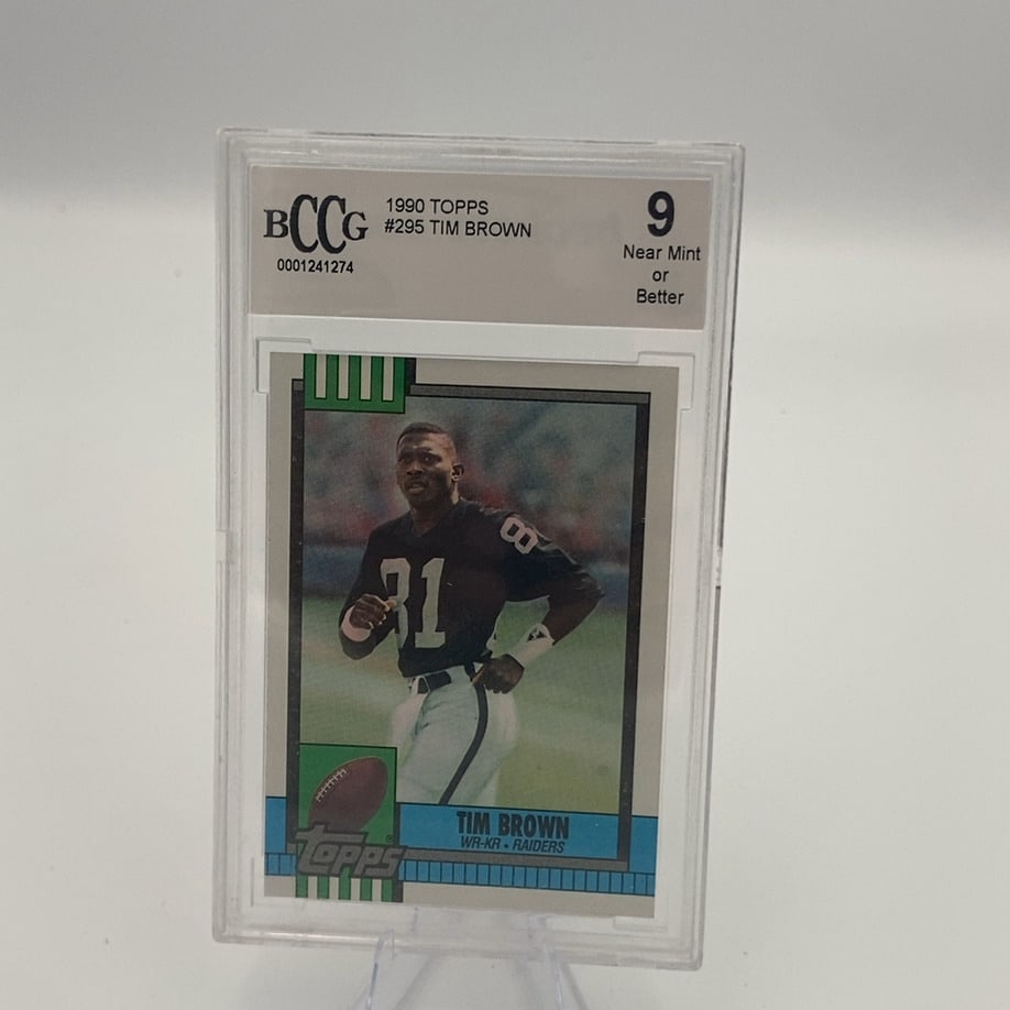 1990 Topps football card featuring Tim Brown: This is a 1990 Topps football card featuring Tim Brown of the Los Angeles Raiders. The card is professionally graded by BCCG with a grade of 9, Near Mint or Better.
