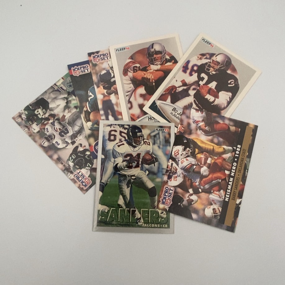 Assorted Pro Set and Fleer NFL Football Cards: A collection of vintage NFL football cards from the early 1990s, featuring brands like Pro Set and Fleer. The assortment includes cards of Hall of Famers Bo Jackson (1990 Fleer), Barry Sanders (1991 P