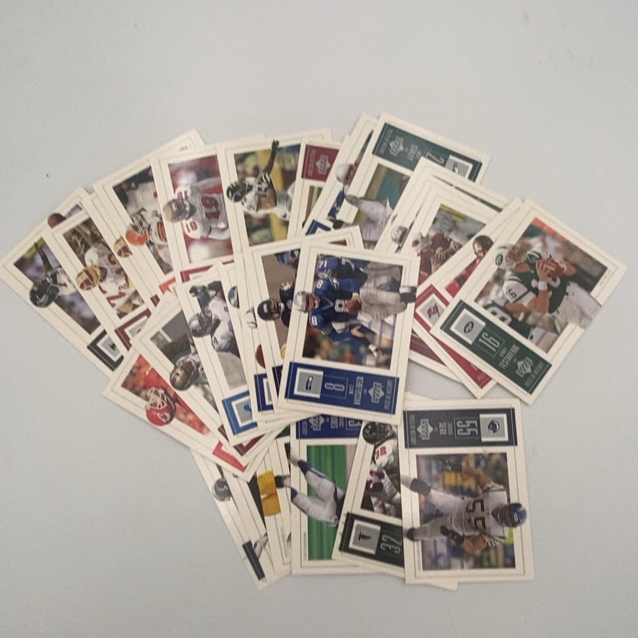 Upper Deck Piece of History NFL Football Card Collection: This is a collection of assorted Upper Deck 'Piece of History' NFL football trading cards fanned out on a flat surface. The cards feature various players in action shots with team logos, player names,