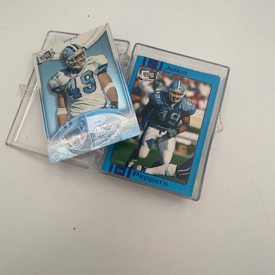 2002 Press Pass JE Julius Peppers: This image features two 2002 Press Pass JE (Jackpot Edition) trading cards of NFL player Julius Peppers, both encased in clear protective plastic holders. The cards show Peppers wearing his number 49
