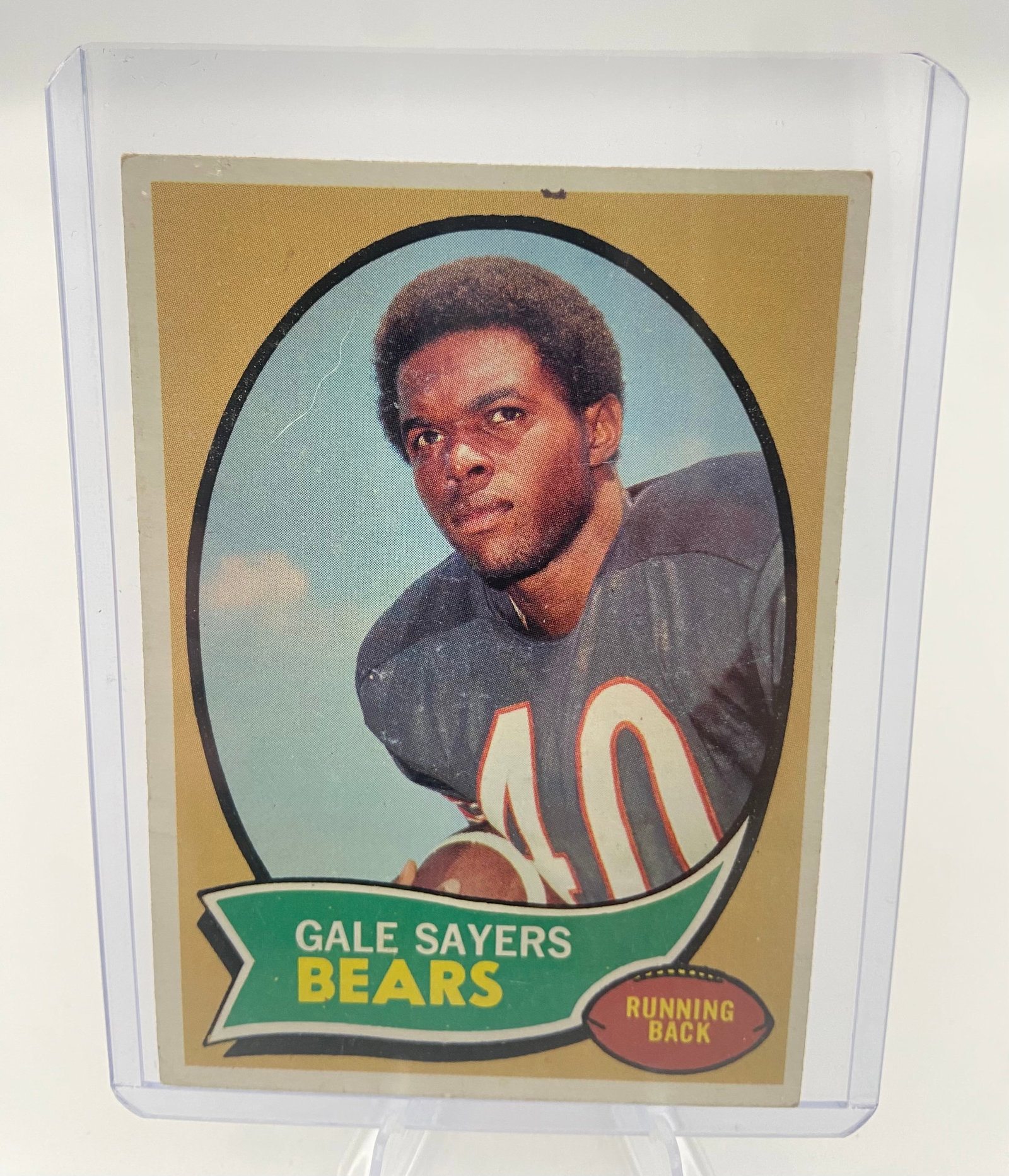 1970 Topps Gale Sayers Chicago Bears Football Card: This is a 1970 Topps football trading card featuring Hall of Fame running back Gale Sayers of the Chicago Bears. The card showcases a portrait image within a gold border and a green name banner. It is