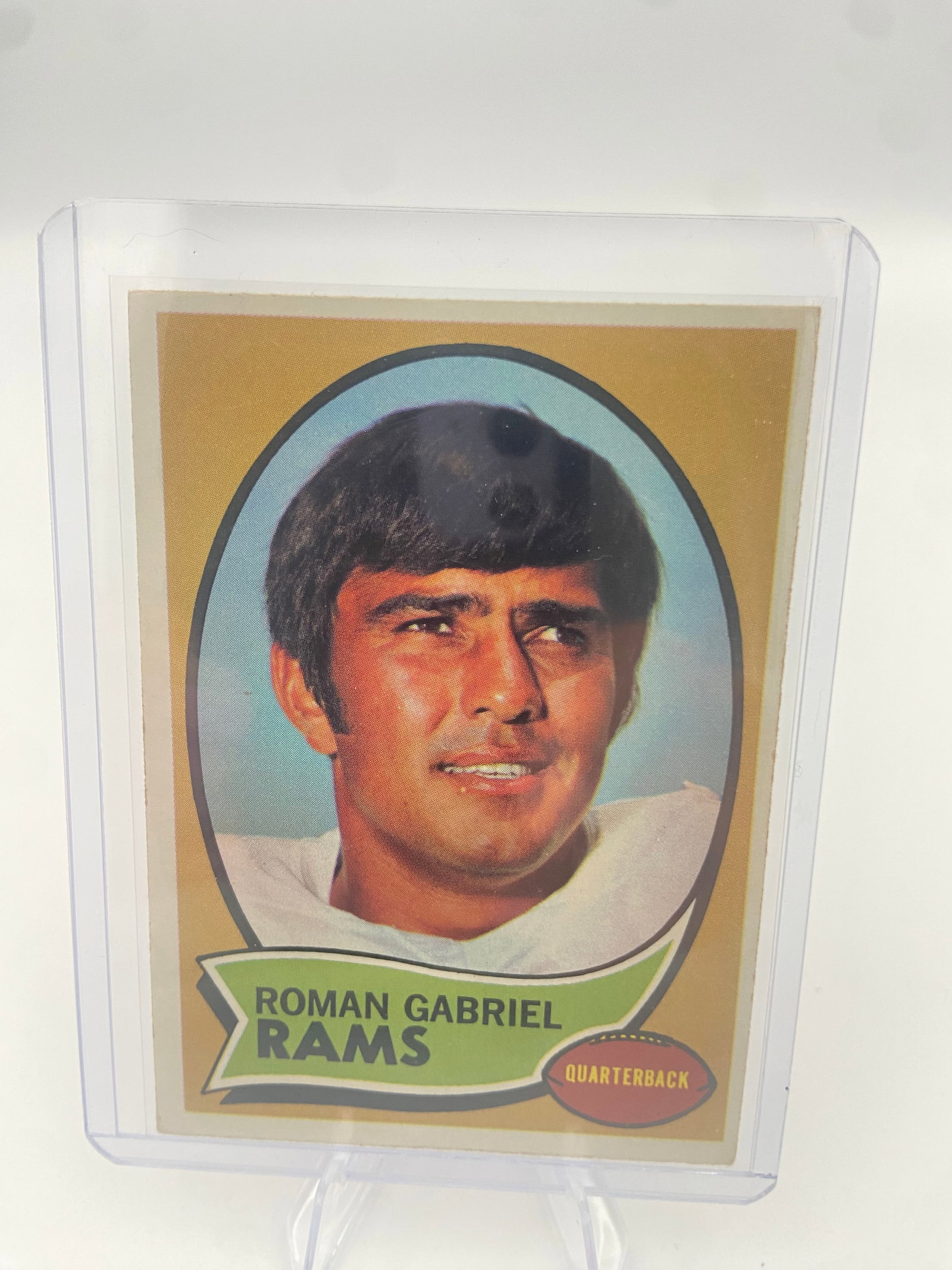 1970 Topps Roman Gabriel Football Card: This is a 1970 Topps football card featuring quarterback Roman Gabriel of the Los Angeles Rams. The card is enclosed in a protective plastic top loader. It is a classic vintage sports card from the 19